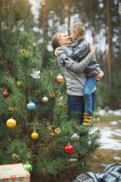 Boules de sapin de Noël sur une branche de pin naturel dans la forêt d'hiver. Mère et fils se câlinent sur le fond. Concept de Noël, Nouvel An et hiver Vacances de Noël, fond, texture — Photo