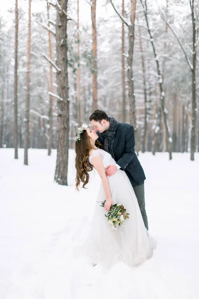 Vinterbröllop. Vackra unga par, omfamna och kyssas i vintern snöig skog. — Stockfoto