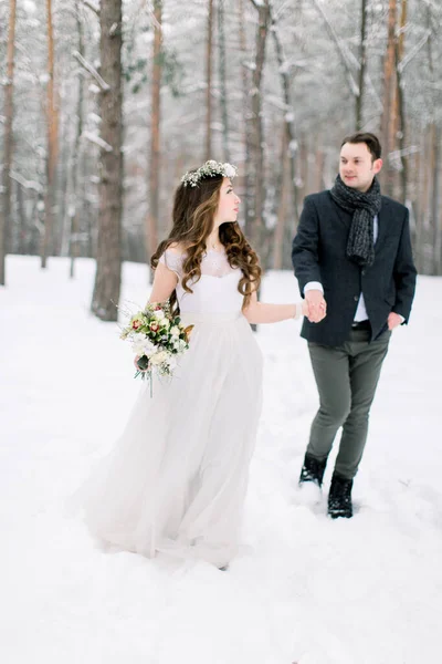 Nevěsta a ženich se dívají jeden na druhého a procházejí se v zimním lese. Detailní záběr. Zimní svatební obřad. — Stock fotografie