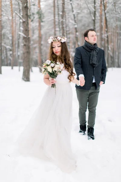 Krásný svatební pár na jejich zimní svatbě, procházky v zimě zasněžený les — Stock fotografie