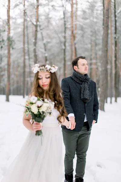 Beautiful wedding couple on their winter wedding, walking in winter snowy forest