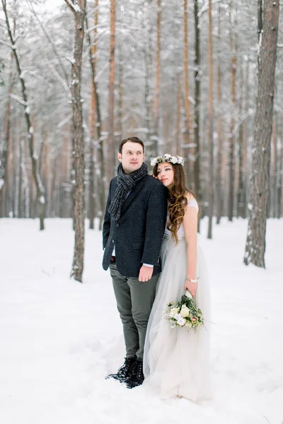 Zimní svatební pár, nevěsta a ženich objímání v zasněženém lese na jejich svatební den — Stock fotografie