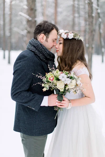 Зимняя свадебная пара, невеста и жених обнимаются в заснеженном лесу в день свадьбы — стоковое фото