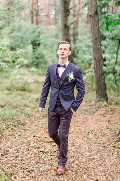 Przystojny pan młody w stylowym garniturze spacerujący po lesie. Stylowe zdjęcie pana młodego. Rustykalny portret ślubny. — Zdjęcie stockowe