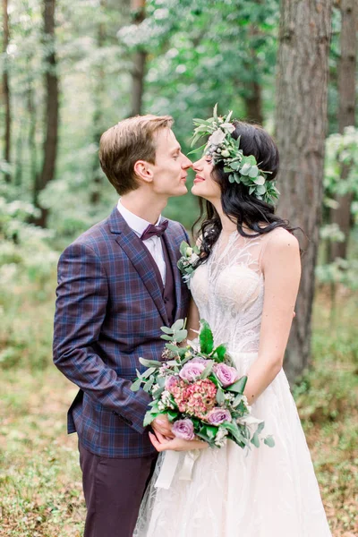 Жених и невеста в лесу целуются. молодожены жених и невеста на свадьбе в природе, зеленый лес, целуются и улыбаются. Сельская свадебная пара — стоковое фото