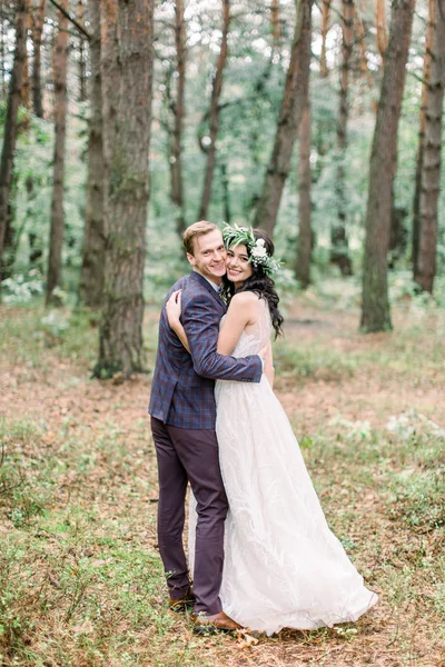 Великолепная свадьба деревенская пара обнимающая, улыбающаяся и гуляющая в лесу — стоковое фото
