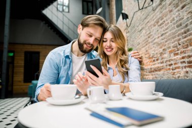 Bir kahveyle geziye hazırlanıyorum. Masada oturan, kahve ya da çay içen, telefon kullanan mutlu bir çift. Pasaportlar ve biletler masaya.