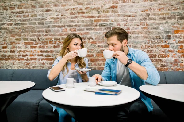 Šťastný mladý pár s pasy a lístky, sedí u stolu a pije kávu, před cestou. Hotelová lobby kavárna, čekárna — Stock fotografie