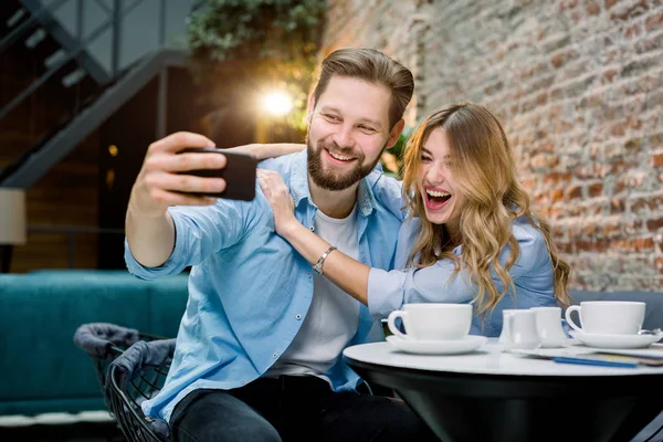 Pár si spolu užívají čas, dělají selfie, sedí u stolu v kavárně a pijí kávu. Pár baví před cestou v čekárně — Stock fotografie