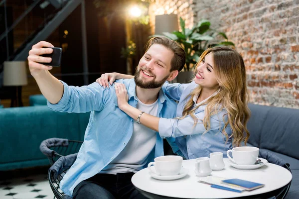 Pár si spolu užívají čas, dělají selfie, sedí u stolu v kavárně a pijí kávu. Pár baví před cestou v čekárně — Stock fotografie