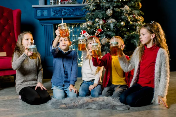 Vrolijk kerstfeest en Happy Holidays. Jonge kinderen limonade drinken en vertellen elkaar kerst verhalen en lach — Stockfoto