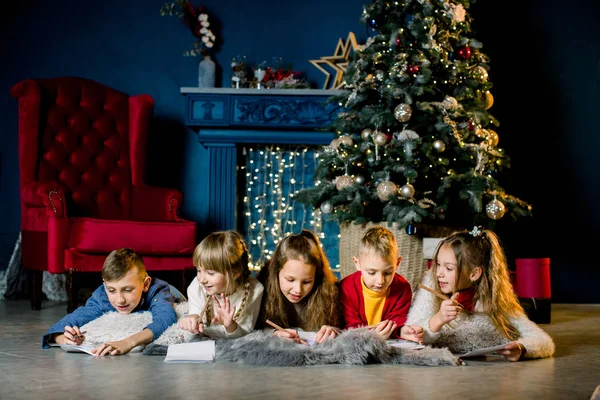 Les petits enfants écrivent une lettre de vœux au Père Noël et se racontent des histoires de Noël — Photo
