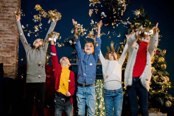 Joyeux cinq enfants caucasiens jettent des confettis et fêtent Noël. Vacances d'hiver et Nouvel An concept . — Photo