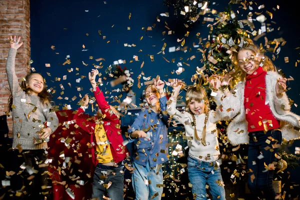 Petits enfants charmants et beaux jouant avec des confettis pendant des vacances sur le fond d'une décoration de Noël. Concept hiver et Nouvel An . — Photo