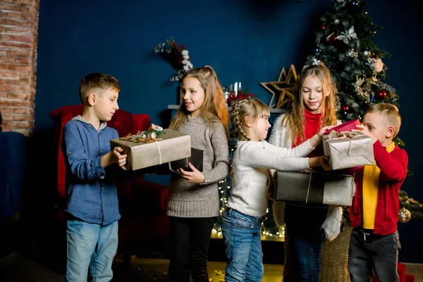 Kleine mooie kinderen zijn blij om giften op Kerstmis en tonen ze aan elkaar — Stockfoto