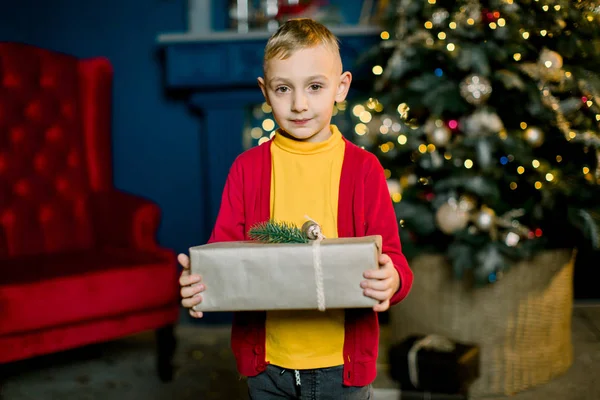 Petit garçon sourit et tient un cadeau de Noël à la veille des vacances . — Photo