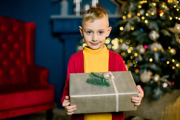 Petit garçon sourit et tient un cadeau de Noël à la veille des vacances . — Photo