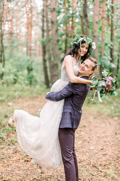 Wedding in pine forest. Man and woman in the autumn forest. Hug love couple, man holds woman on hands