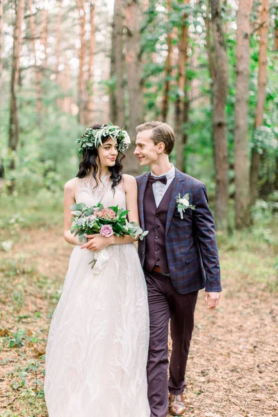 Gorgeous wedding rustic couple hugging, smiling and walking in forest