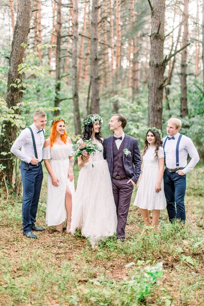 Groom with bride and their friends. Autumn rustic wedding in the pine forest. Cheerful friends. Wedding day after wedding ceremony