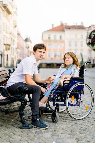 Junge Männer und Frauen im Rollstuhl haben Spaß und lächeln auf der Bank draußen. Altstadtstraße, Liebes- und Behindertenkonzept — Stockfoto