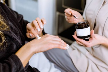 Alerji testi ve kozmetoloji konsültasyonu. Profesyonel kadın kozmetolojistin müşterisi için krem sürerken alerji testi yaparken çekilmiş görüntüsü. Kadın müşteri eline krem sürüyor.