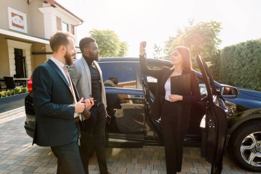 Yandan bakan genç bayan danışmanın fotoğrafında panoda alıcılara, Afrikalı ve Kafkas erkeklerine ait araba anahtarlarını gösteren bir pano var. Araba kiralama kavramı