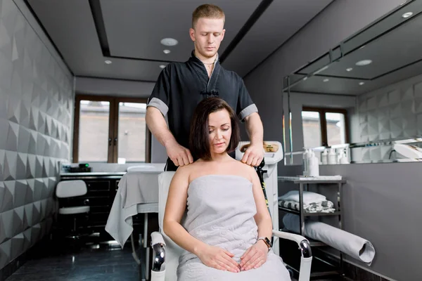 专业男性理疗师手工按摩年轻女子肩部及后背至复康科诊所 — 图库照片