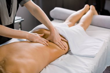 Modern tıp merkezindeki kanepede uzanmış kadın masörün kadın müşterisine masaj yaparken çekilmiş bir fotoğrafı.