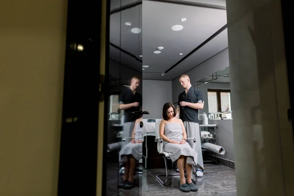 Young man therapist doing ultrasound cavitation body contouring treatment, vacuum anti-cellulite massage on the shoulders and back of pretty female client. Full-lengh photo, spa medical center