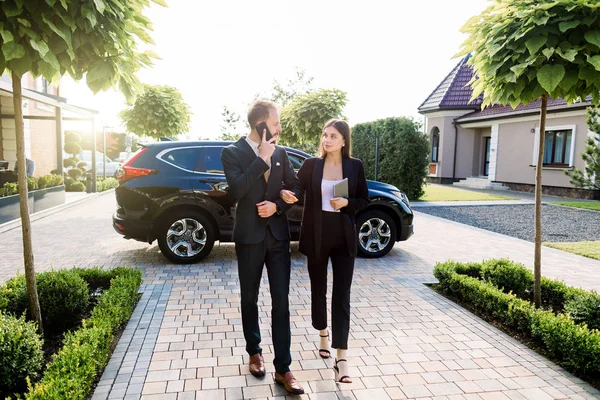 Longitud completa de hombre de negocios y mujer de negocios caminando fuera del edificio de oficinas en la reunión de negocios, al aire libre, en el fondo de los edificios de automóviles y centros de oficinas. Reunión de empresarios — Foto de Stock