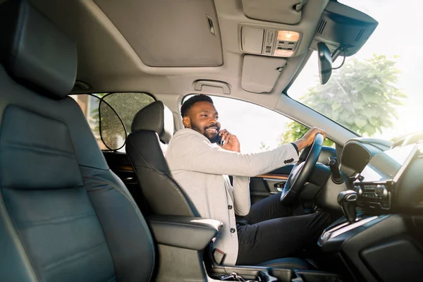Negro hombre de negocios guapo conducir el coche hablando en el teléfono inteligente . — Foto de Stock