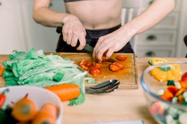 Yeni mutfakta yemek pişiren bir kadın sebzelerle sağlıklı yemekler yapıyor. Yirmili yaşlarda beyaz bir kadın.