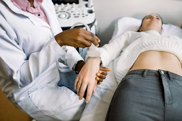 Close-up de mão médica mulher africana com scanner de ultra-som fazendo o exame na mão de paciente jovem — Fotografia de Stock