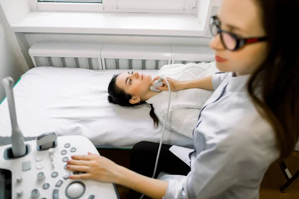 Молодая белая женщина проходит УЗИ щитовидной железы в женском отделении. Молодая женщина делает УЗИ шеи в больнице — стоковое фото