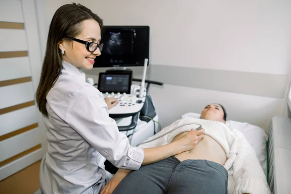 Ultrasound diagnostics of a young woman by modern ultrasound equipment. Pregnant woman getting ultrasound from female doctor — Stock Photo, Image