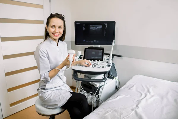 Retrato de mulher branca sorridente jovem médico, operador de máquina de varredura de ultra-som 4D, segurando scanner de ultra-som e esperando pelo paciente — Fotografia de Stock