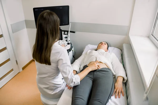 Ультразвуковая диагностика молодой женщины с помощью современного ультразвукового оборудования. Беременная женщина получает ультразвук от женщины-врача — стоковое фото