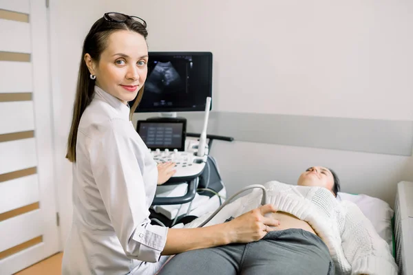 Красивая женщина-врач, оперирующая современным ультразвуковым сканером при обследовании живота и мочевого пузыря пациентки — стоковое фото