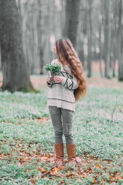 Bela jovem mulher caminhando pela floresta verde na primavera, segurando ar de vidro com flores brancas da primavera — Fotografia de Stock