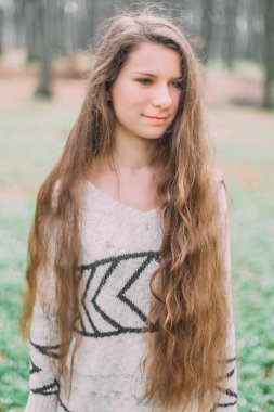 Süveter giymiş güzel bir kadın koşuyor ve sabah yeşil ormanda yürüyor.