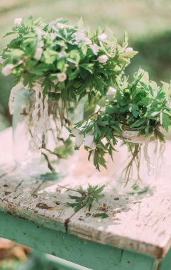 Cam kavanozda bir buket beyaz bahar çiçeği Ormanda tahta sandalyede açık havada