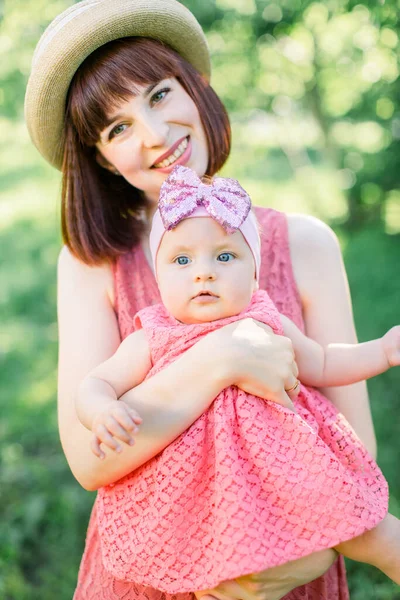藁帽子の美しい母と彼女の小さな娘屋外の家族はピンクのドレスで見ています。幸せな家族の屋外肖像画。家族みたいに肯定的な人間の感情感情感情感情. — ストック写真
