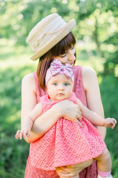 Красива мати з солом'яним капелюхом І її маленька донька на відкритому повітрі сімейство дивляться в рожеве плаття. На відкритому повітрі Портрет щасливої родини. сімейний погляд. Позитивні людські емоції, почуття, емоції . — стокове фото