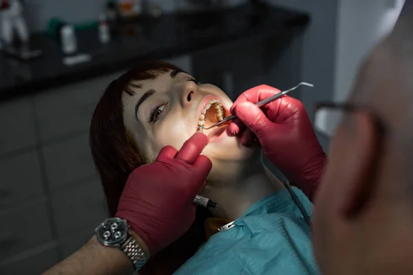 Mooie jonge vrouw met open mond bij tandarts met tandheelkundige behandeling bij tandartsen kantoor. — Stockfoto