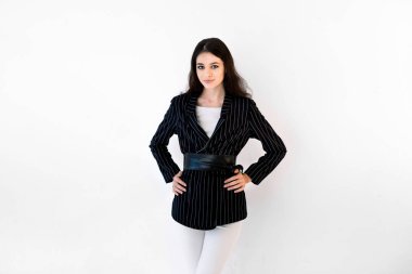 Confident young female manager on white background. Portrait of smiling business woman, wearing white pants and black jacket