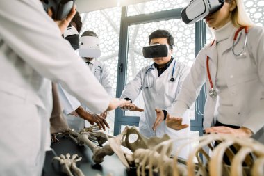 Group of multiethnic scientists, boiengeneers or doctors wearing virtual reality digital glasses looking at human skeleton, virtual anatomy. Healthcare medical, vr headset vision concept