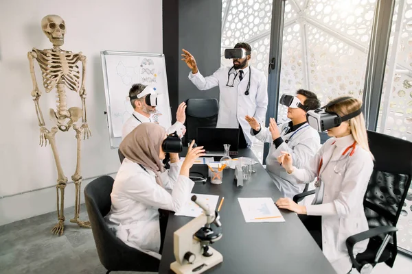 Group of multiethnic students with professor learn medicine or scientific project with vr glasses in modern laboratory. Medical research, chemistry, science, vr concept