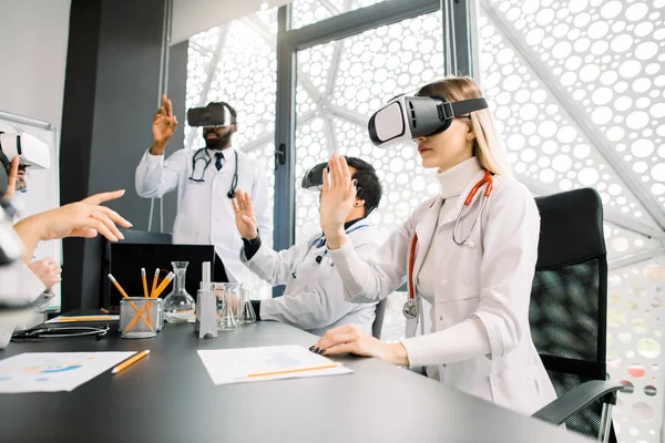 science, future technology, medicine and chemistry concept - young multiracial doctors or scientists in white lab coats and vr glasses working with new research, touching to virtual screen