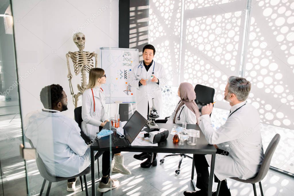 Chemical lab workers, doctors, scientists having a meeting. Asian man explaining a new project concept for his colleagues. Scientific discovery, medical research, scientists teamwork